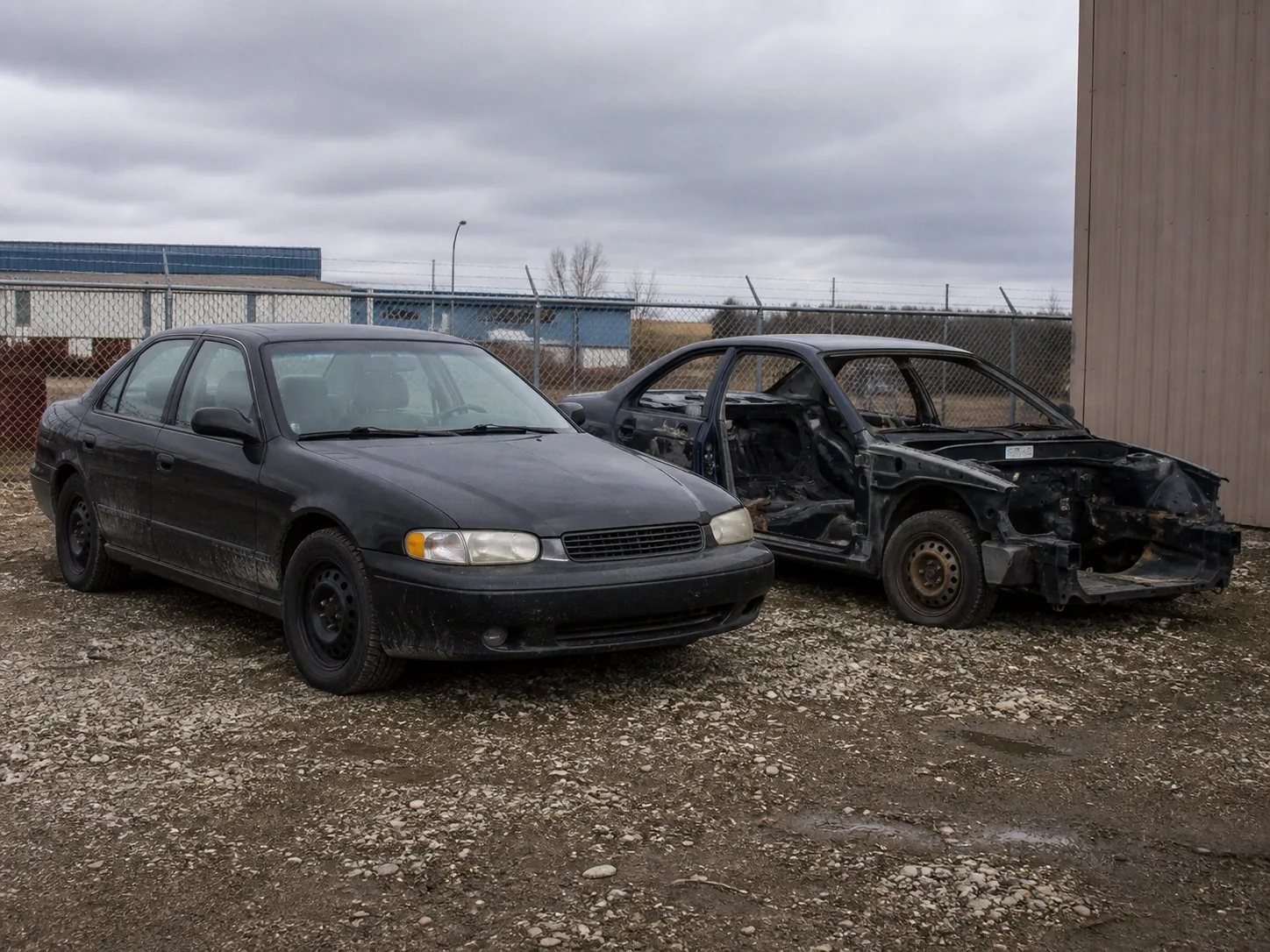 An intact end-of-life car beside a more stripped metal-value vehicle.