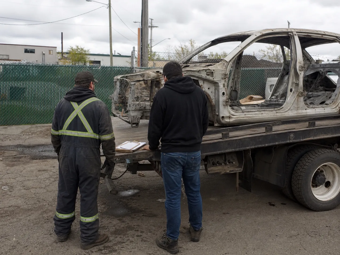 An operator assessing a metal-value-only vehicle with its parts gone.